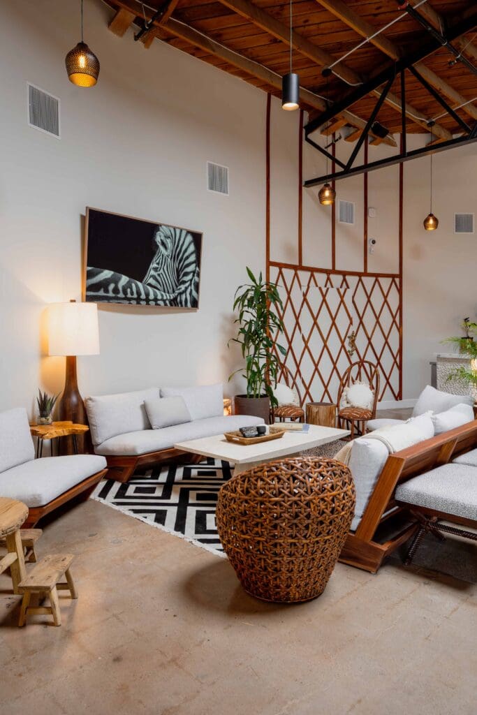 Biophilic hospitality lounge with natural wood furniture, woven textures, indoor plants, warm lighting, and an open layout designed to support guest comfort and connection.