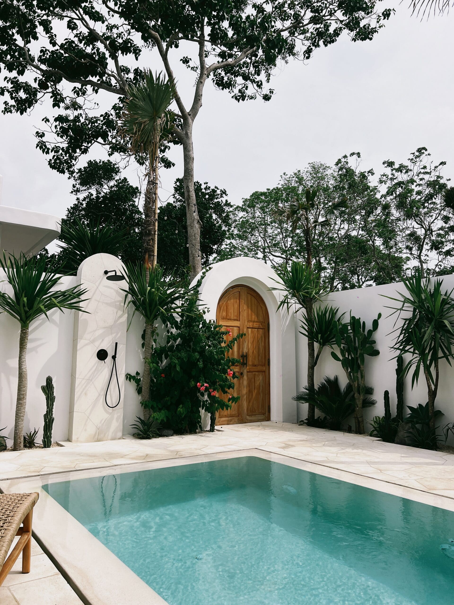 Biophilic design example featuring a hospitality courtyard with natural materials, tropical landscaping, organic architecture, and a tranquil pool supporting guest well-being.